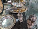 une vitrine en verre contenant de la vaisselle et des couverts en argent
