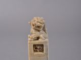 carved ivory figurine of a lion on a pedestal on a gray background