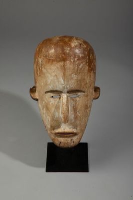 tête d'homme sculptée posée sur un socle noir, sur fond blanc