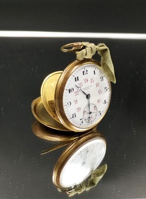 une montre de poche en or posée sur une table en verre