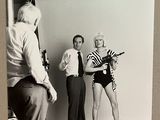 photographie en noir et blanc de deux hommes et d'une femme debout devant un appareil photo