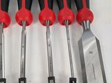 six red and black tools are lined up on a white surface
