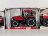 three red toy tractors in boxes on a white surface