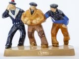 trois figurines représentant des hommes debout sur un socle en bois