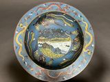 a blue and yellow plate with a picture of a mountain scene on it