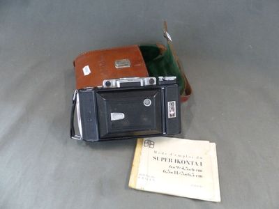 un petit appareil photo posé sur une table, à côté d'une feuille de papier