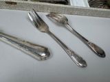 three silver spoons and two silver forks on a table