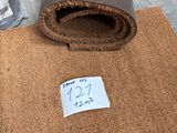 a roll of brown carpet on the ground next to a plastic bag