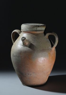 un vase marron posé sur une table sur fond noir