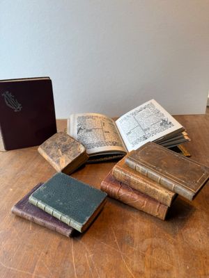 several old books are sitting on a wooden table next to a book case