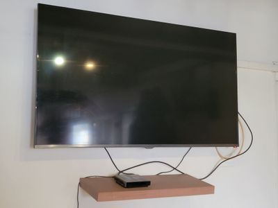 une télévision à écran plat fixée au mur au-dessus d'une étagère