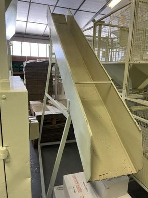 Dans un entrepôt, des cartons sont empilés sur un tapis roulant