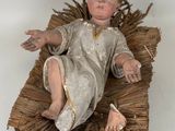 a small doll of a baby laying on a blanket