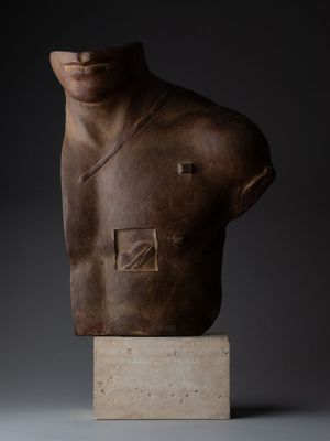 Une sculpture représentant le torse d'un homme est représentée sur un fond sombre.