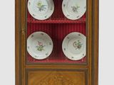 une vitrine contenant des assiettes et dotée d'une porte vitrée