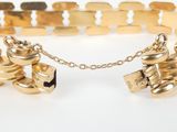 a close up of a gold bracelet on a white surface