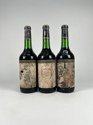 trois bouteilles de vin posées les unes à côté des autres sur une surface blanche