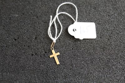 un petit collier avec une croix en or et une plaque accrochée dessus