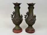 pair of antique bronze vases on marble bases on a white background