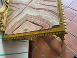 a marble table with a gold frame and a clock on it