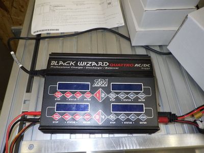 une photo d'un chargeur de batterie « Wizard » noir posé sur une table