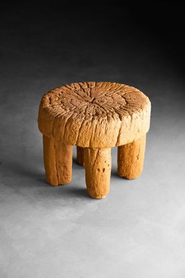 une image représentant un petit tabouret en bois posé sur une surface grise