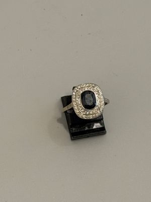 une photo d'une bague sertie d'un diamant et d'un saphir, posée sur un présentoir