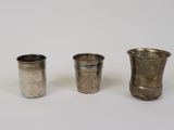 trois tasses en argent posées l'une à côté de l'autre sur une surface blanche