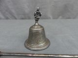 a silver bell with a bird on top of it