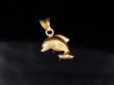 a close up of a gold dolphin pendant on a black background