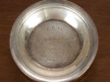 une assiette en argent posée sur une table en bois, sur laquelle figurent des inscriptions