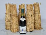 a bottle of wine sitting next to a bunch of straw