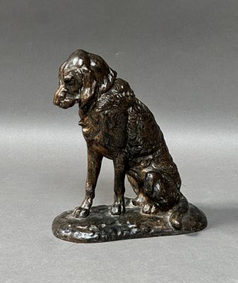 bronze statue of a dog sitting on a rock on a gray surface