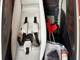 an open trunk of a car with a seat and umbrellas in it
