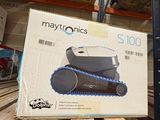 une caisse de Maytronics posée sur une palette dans un entrepôt