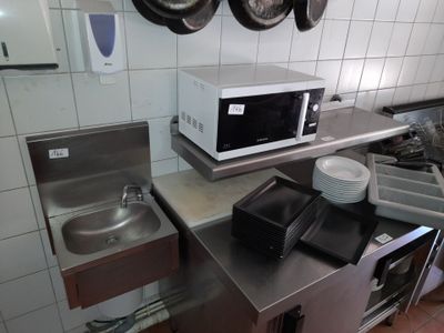 une cuisine équipée d'un micro-ondes, d'un évier et de casseroles accrochées au mur