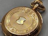 a gold pocket watch on a chain on a table