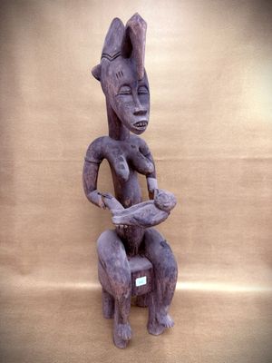 sculpture of a woman sitting on a stool holding a bird