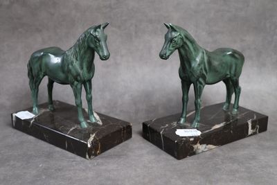 une paire de statues de chevaux en bronze sur des socles en marbre, sur fond gris