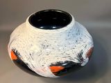 a black and white vase with orange designs on it