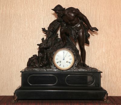 une statue représentant un homme avec un chien et une horloge posée sur une table