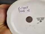 a person holding a white porcelain object with a sticker on it