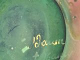 a green vase with writing on it sitting on a table