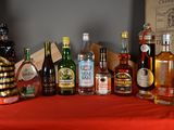 many bottles of alcohol on a table with a red table cloth