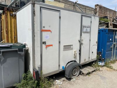 une photo représentant des toilettes portables au milieu d'un jardin