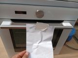 a person holding a piece of paper in front of an oven