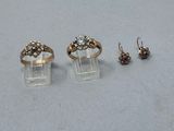 deux bagues en or et une paire de boucles d'oreilles posées sur une table