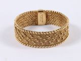 a close up of a gold bracelet on a white background
