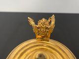 a close up of a gold plate with a bird on top
