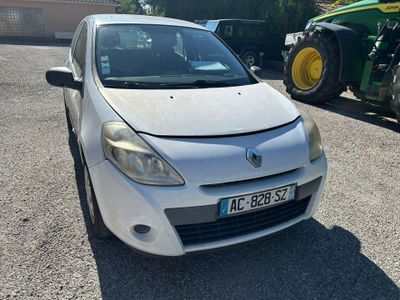 une petite voiture blanche garée sur un parking, avec un tracteur derrière elle